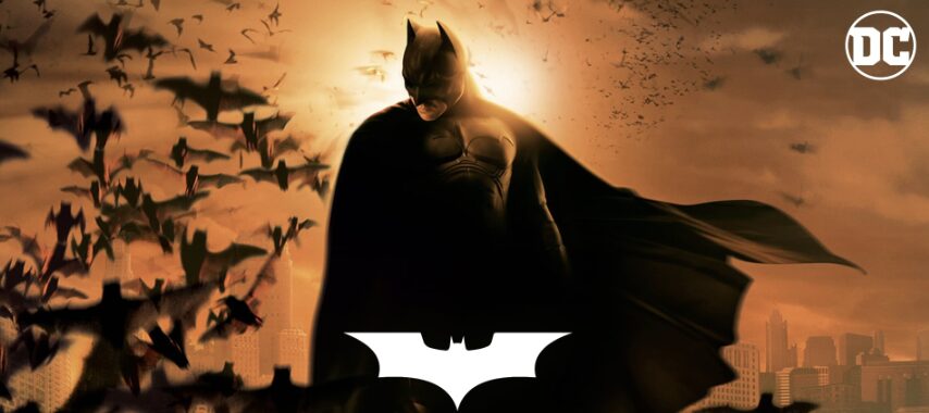 映画『バットマン ビギンズ』のビジュアル。夕焼けのゴッサムで、コウモリの群れを背に立つバットマンのシルエットが描かれている